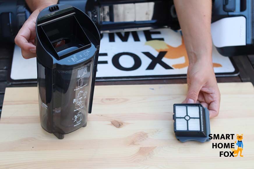 Man sieht, wie der HEPA-Filter aus dem Schmutzbehälter genommen wird. 