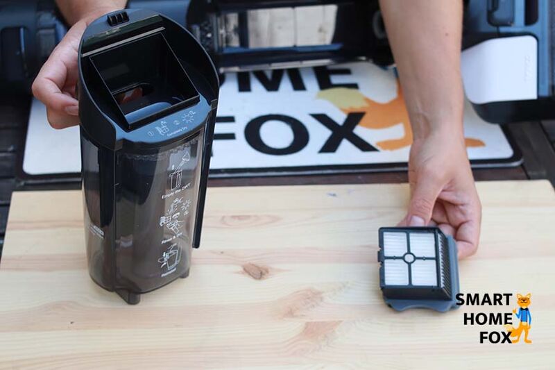 Man sieht, wie der HEPA-Filter aus dem Schmutzbehälter genommen wird.