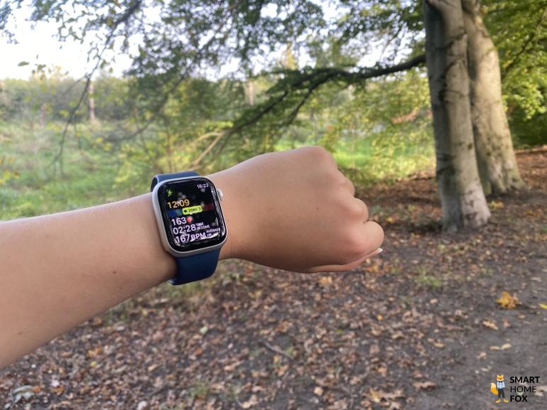 Apple Watch 9 mit geöffneter Aktivität “Laufen” mit Bäumen im Hintergrund