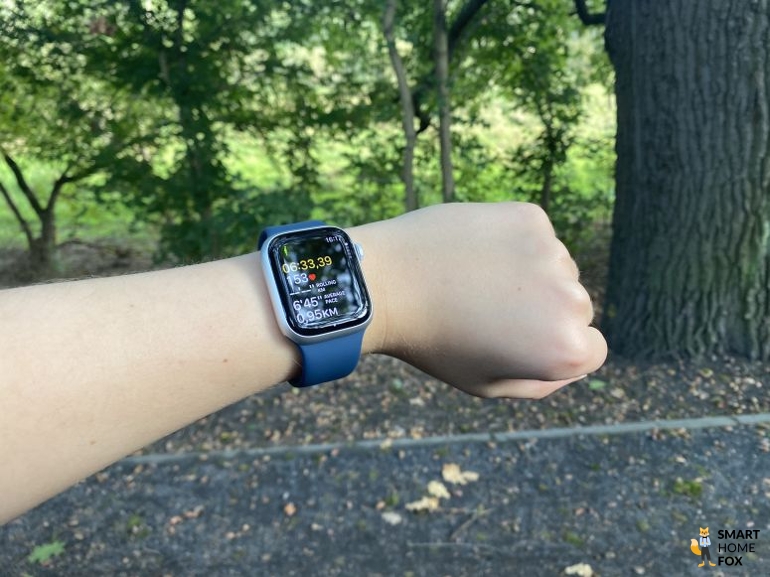 Apple Watch 9 mit geöffneter Fitness App und Bäumen im Hintergrund