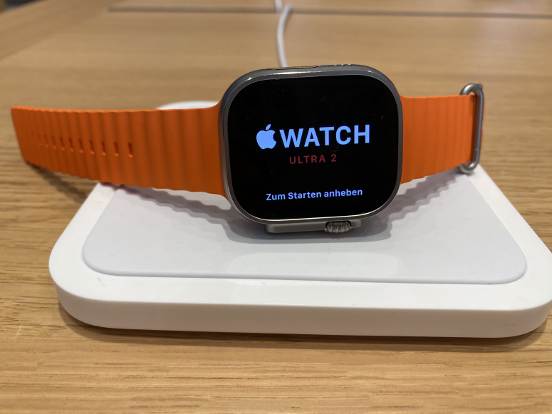 Apple Watch Ultra 2 auf Ladepad mit orangenen Armband