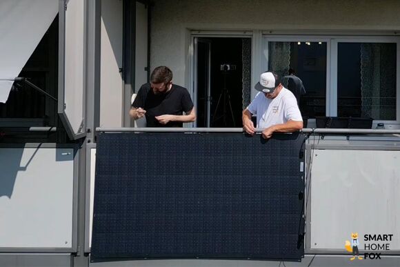 Ein leichtes und flexibles Balkonkraftwerk Solarmodul wird von zwei Balkonkraftwerk Experten am Balkongeländer befestigt.