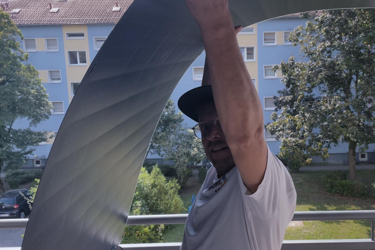 Das Solago 800 W Balkonkraftwerk mit flexiblen und super leichten Solarmodulen wird präsentiert und das Ultraleichte und biegsame Solarmodul wird in der Hand über dem Kopf gehalten und biegt sich.