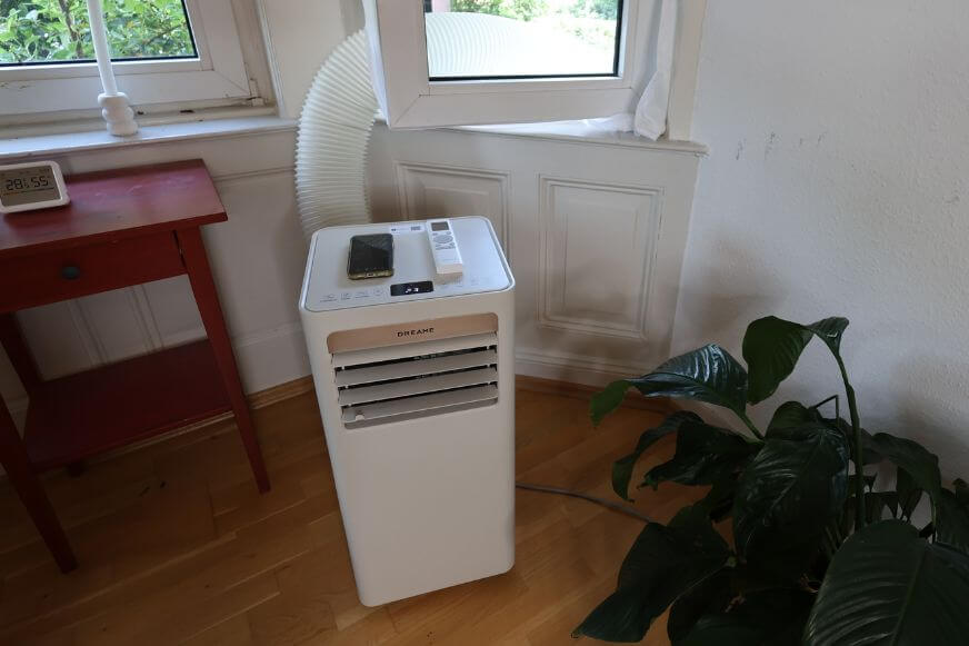 Dreame P-Wind 10 mobile Klimaanlage steht mit aus dem Fenster hängenden Abluftschlauch im Büro auf dem Boden