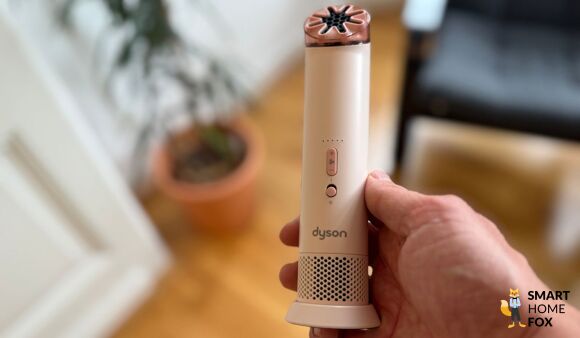 Dyson HushJet Mini Cool wird in der Hand gehalten, Seitenansicht vor hellem Hintergrund