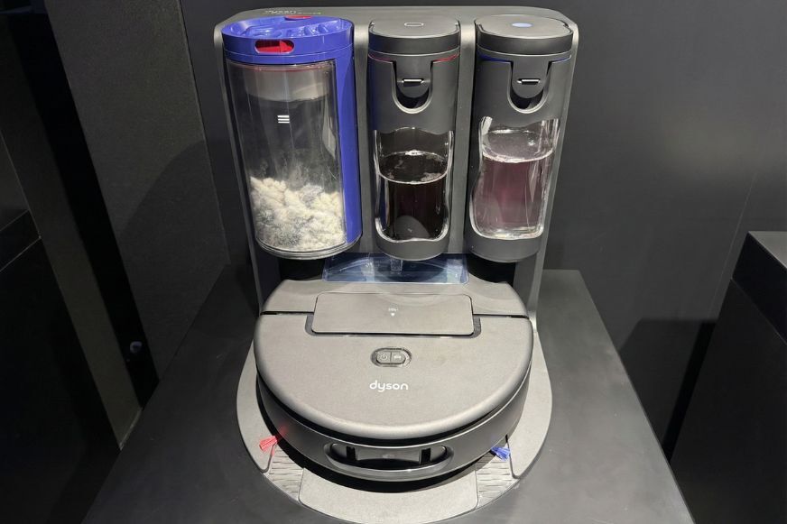 Der Dyson Spot+Scrub Ai Saug- und Wischroboter steht neben seiner kompakten Absaugstation.