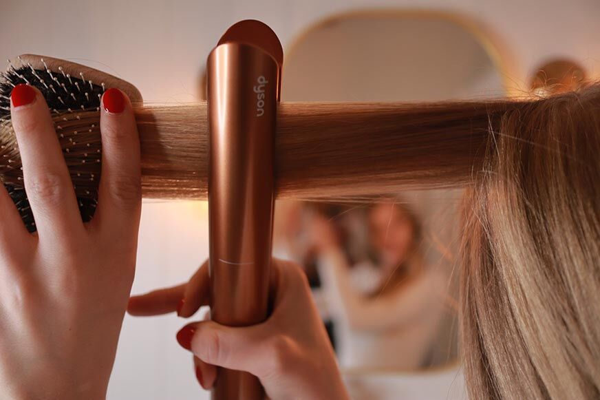 Man sieht, wie die Haare mit dem Dyson Corrale geglättet werden.