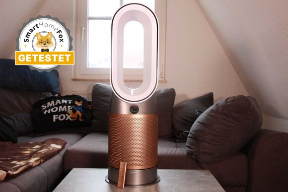 Der Dyson Purifier Hot+Cool Formaldehyde HP09 Luftreiniger, Heizlüfter und Ventilator steht vor einer Couch auf einem Couchtisch.