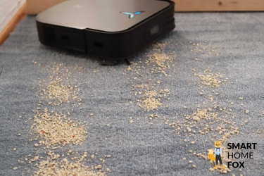 Der ECOVACS DEEBOT X2 OMNI saugt auf dem Teppichboden Haferflocken.