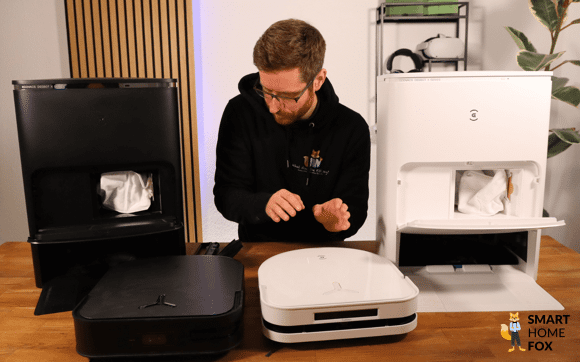 Der DEEBOT X5 OMNI und der X3 OMNI stehen auf dem Tisch nebeneinander, mit den Stationen im Hintergrund.