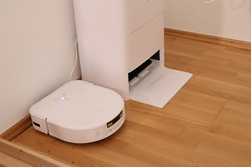 ECOVACS DEEBOT X5 OMNI und die OMNI Station stehen nebeneinander auf dem Laminat
