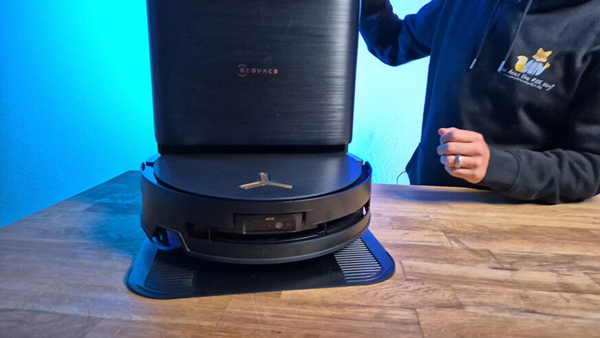 Der ECOVACS DEEBOT X9 PRO OMNI beim Wischen auf Parkett mit sichtbarer Station im Hintergrund.