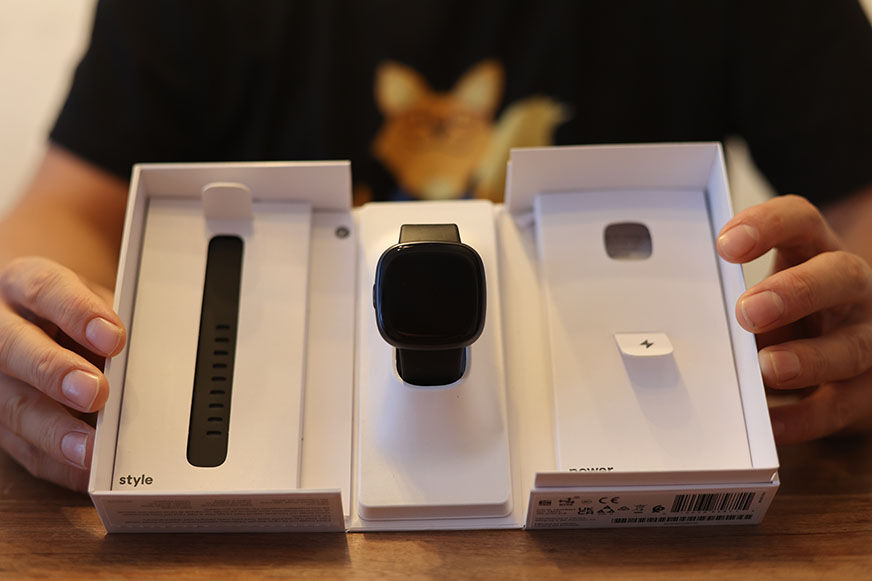 Man sieht die Fitbit Versa 4 in ihrem Karton.