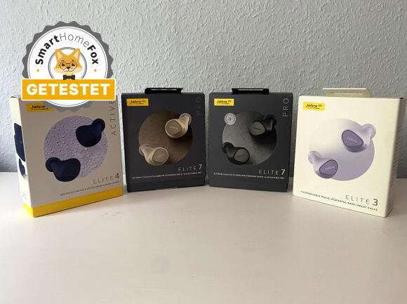 Jabra Elite 3 in Lila, Elite 4 Active in Navy und Elite 7 Pro in Gold und Schwarz mit ihrer Verpackung auf einem Tisch