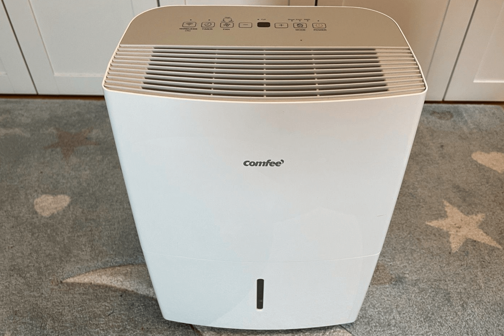 Der Comfee Luftentfeuchter MDDF 20DEN 7 WF steht vor einem blauen Hintergrund.