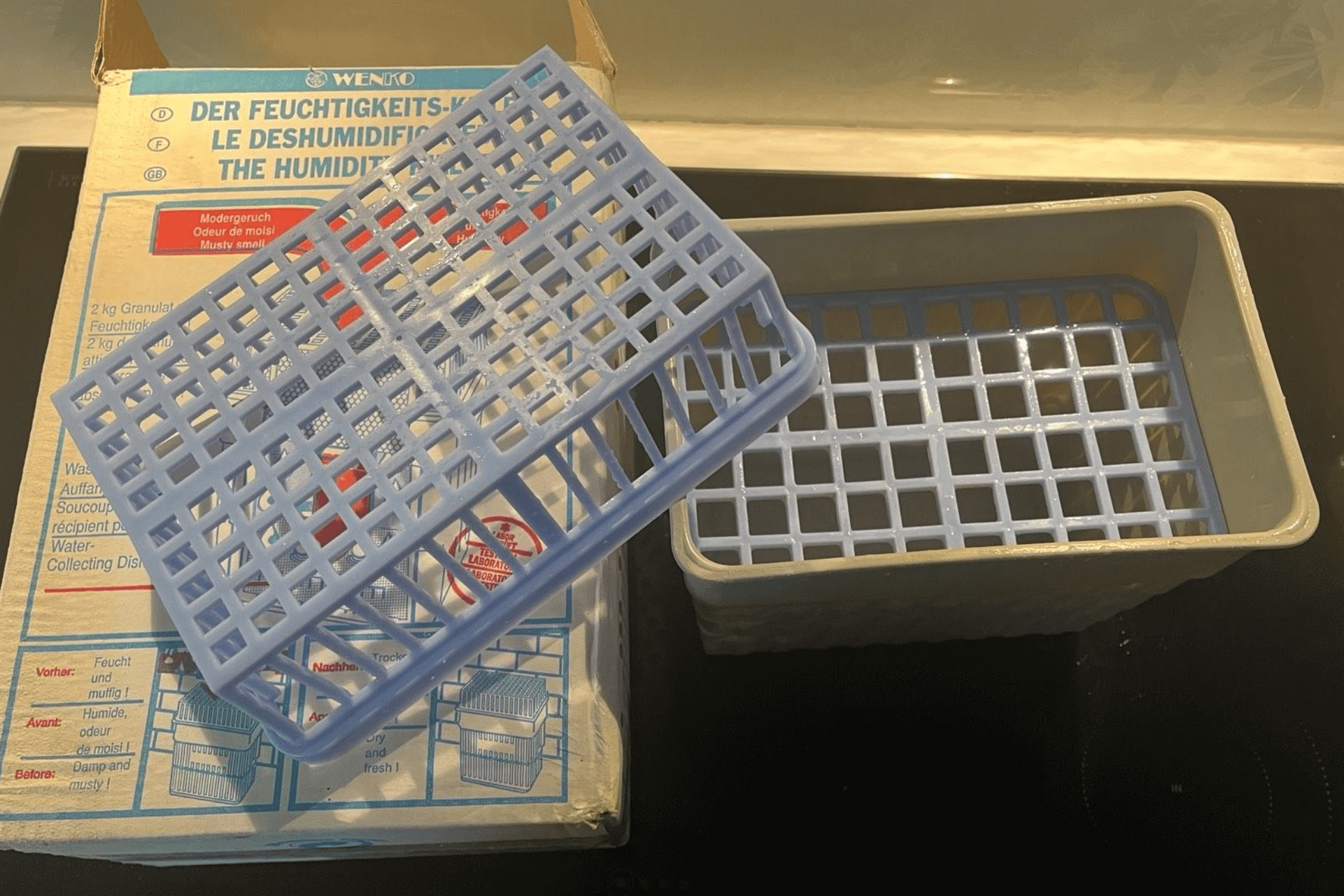 Der Wenko Granulat-Luftentfeuchter steht neben der Originalverpackung.