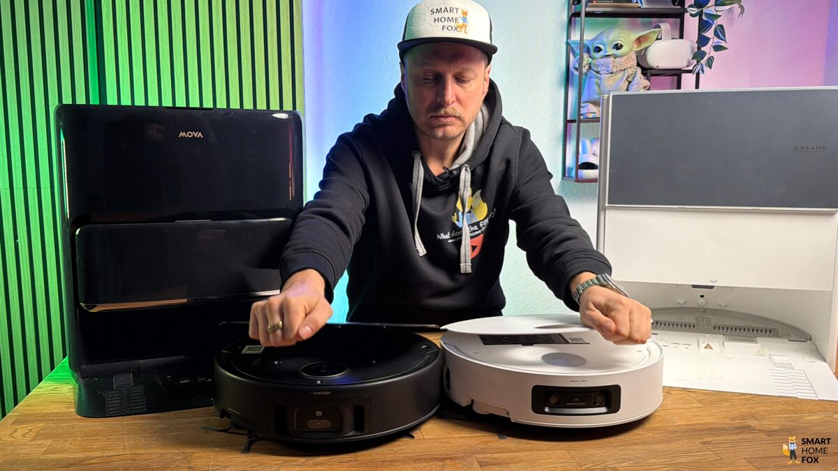 Der Dreame Aqua10 Roller und der Mova Z60 Roller stehen nebeneinander auf einem Holztisch für Vergleichszwecke.