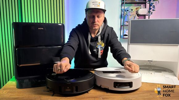 Der Dreame Aqua10 Roller und der Mova Z60 Roller stehen nebeneinander auf einem Holztisch für Vergleichszwecke.