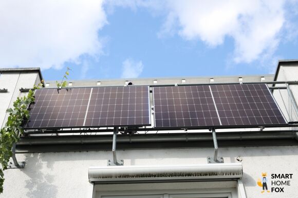 Ein Balkonkraftwerk mit 2 Solarmodulen hängt an einem Balkongeländer.