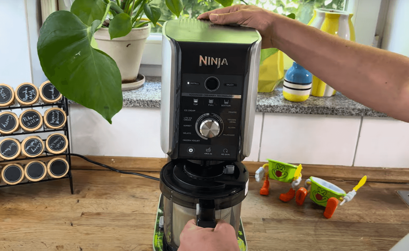 Eine Hand startet den Mixvorgang an der Ninja Creami Deluxe Eismaschine.