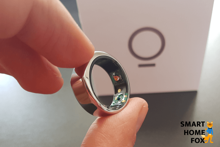 Der Oura Ring wird in der Hand gehalten und im Hintergrund ist die Verpackung zu sehen
