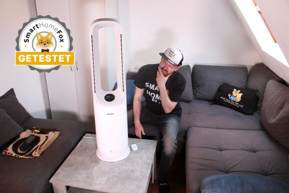 Der Philips Air Performer Series 7000 steht auf einem Couchtisch und daneben sitzt der Smart-Home-Fox Experte Alex und schaut fragend auf den 2 in 1 Luftreiniger und Turmventilator.