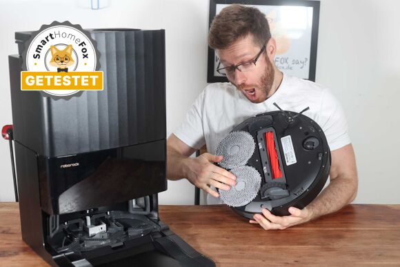 Der Roborock Q Revo steht zu Testzwecken auf dem Tisch und ein Smart Home Fox Mitarbeiter begutachtet diesen.
