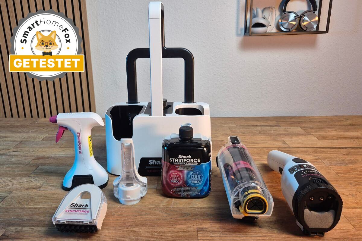 Der Shark Stainforce Fleckenentferner liegt samt Konzentrat, Halterung, Aufsätze und Zubehör bei Smart-Home-Fox auf dem Tisch.