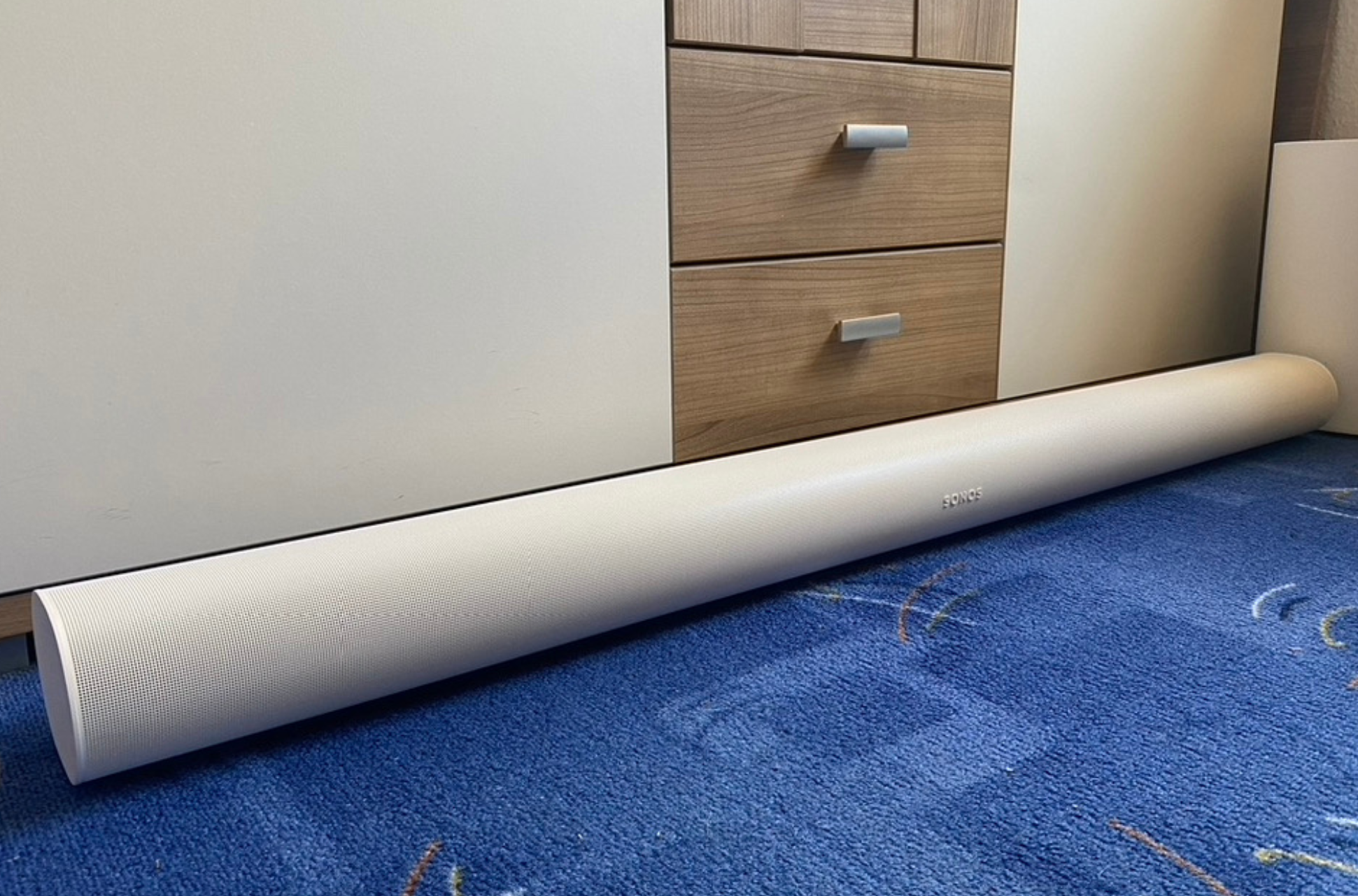 Sonos Arc in weiß auf einem blauen Teppich