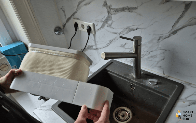 Die einzelnen Komponenten des SwitchBot Luftbefeuchters werden am Waschbecken gereinigt.