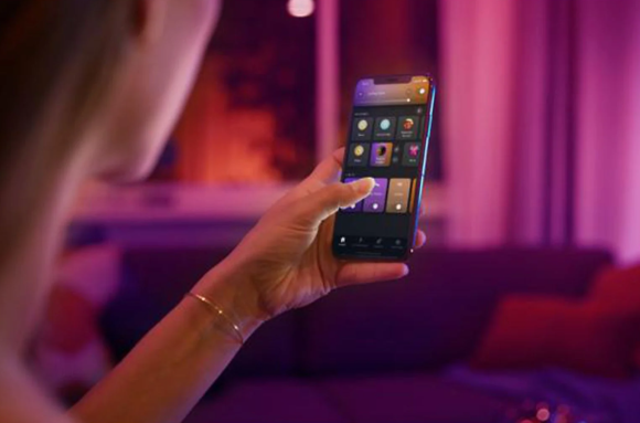 Hand mit Smartphone, dahinter pinkes Licht