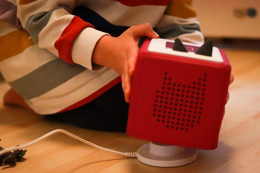 Kind stellt Toniebox auf die Ladestation