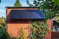 Yuma Front (800W) Pro an einer Backsteinmauer im Garten