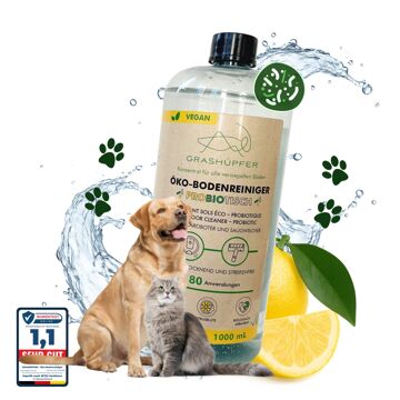 Der probiotische Öko-Bodenreiniger von Grashüpfer ist in einer Flasche zu sehen, daneben sitzen ein Hund und eine Katze, da er gut als natürlicher Geruchsentferner dient und Zitronen symbolisieren den Zitrusduft.