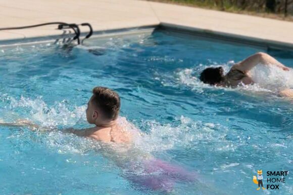 iGarden Swim Jet X Series portable Gegenstromanlage am Poolrand im Test, eine Schwimmering schwimmt gegen den Strom von der Anlage.