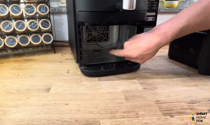 Der Innenraum des Ninja Double Stack wird gereinigt – ein Finger zeigt auf die Krümel-Auffangfläche im unteren Bereich. Die gut erreichbare Fläche erleichtert die regelmäßige Pflege enorm.
